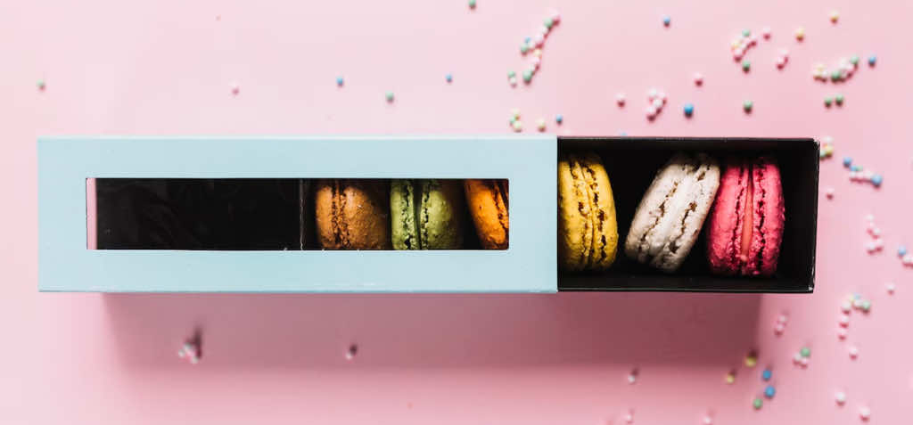 elevated-view-colorful-macaroons-box-pink-background_23-2147957482.jpg
